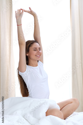 Woman stretching in bed after wake up, entering a day happy and relaxed after good night sleep. Sweet dreams, good morning, new day, weekend, holidays concept