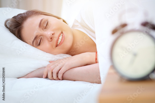 Beautiful young and happy woman sleeping while lying in bed comfortably and blissfully smiling