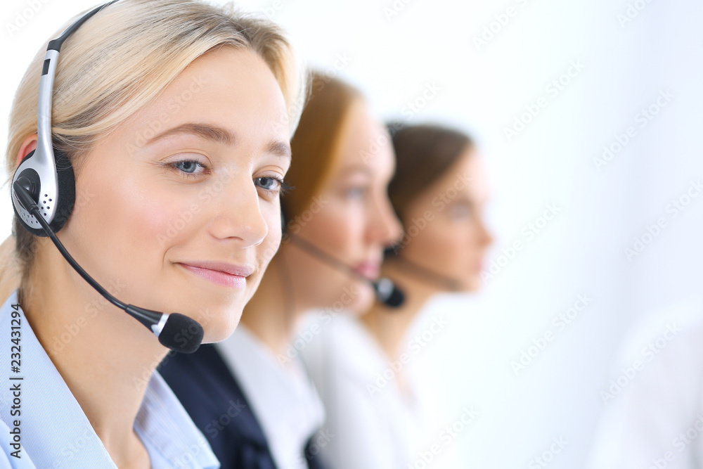 Call center. Group of operators at work. Focus at blonde business woman in headset Call center. Group of operators at work. Focus at blonde business woman in headset