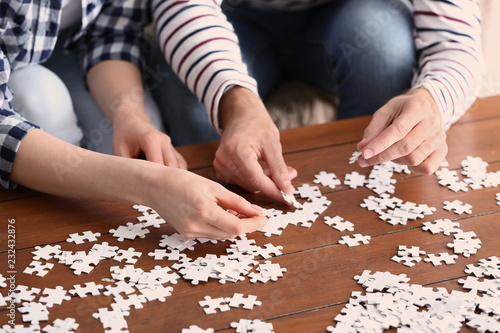 Young couple doing jigsaw puzzle at home, closeup