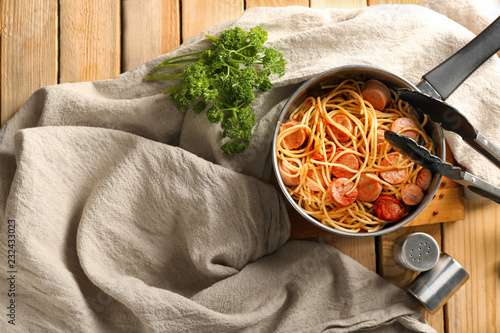 Pot with delicious pasta and sausage on wooden table