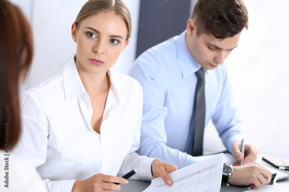 Group of business people or lawyers discussing terms of transaction in office. Colleagues working all together. Focus at blonde woman. Meeting and teamwork concept Group of business people or lawyers discussing terms of transaction in office. Colleagues working all together. Focus at blonde woman. Meeting and teamwork concept