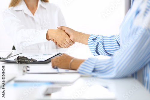 Business handshake at meeting or negotiation in office. Partners shaking hands while satisfied because signing contract or financial papers. Best client service, casual style. Success concept