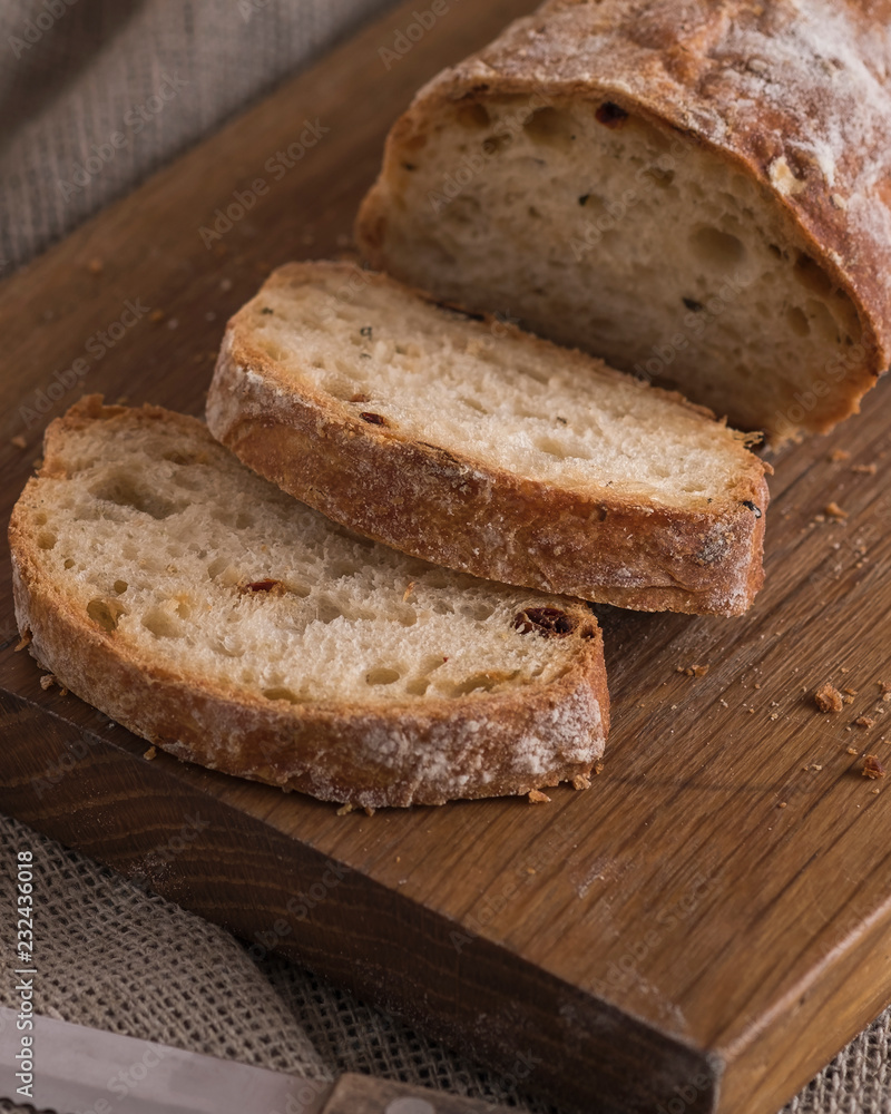 Appetizing sliced ciabatta bread on wooden board.