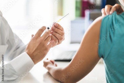 Doctor, patient and injection needle. Physician or nurse giving vaccine, flu or influenza shot in office room in hospital.  Immunity, health care or HPV concept. Medical professional working. photo