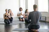 Group of young sporty people practicing yoga lesson with male instructor, doing vajrasana exercise, seiza pose, working out, students training in club, close up view, studio. Healthy, mindful