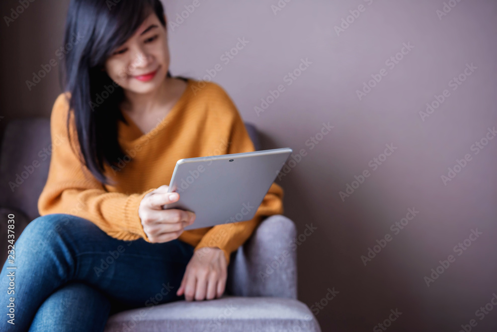 Reading Concept. Young Woman using Tablet and Relaxing on Sofa in Cozy House, Sit on the Chair, Front View and Selective Focus Reading Concept. Young Woman using Tablet and Relaxing on Sofa in Cozy House, Sit on the Chair, Front View and Selective Focus