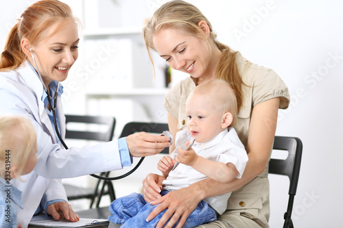 Doctor examining a little boy with stethoscope. Mother holds her son on her lap. Motherless and medicine concept © rogerphoto