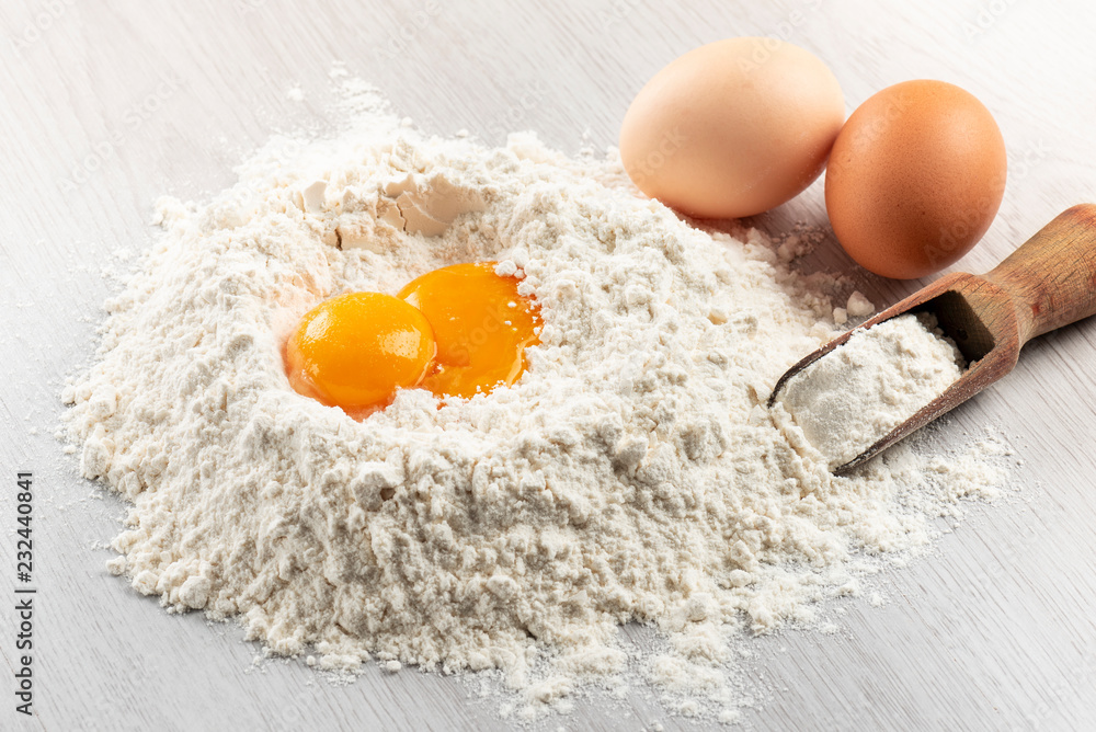 pile of flour with egg yolks for dough on table pile of flour with egg yolks for dough on table