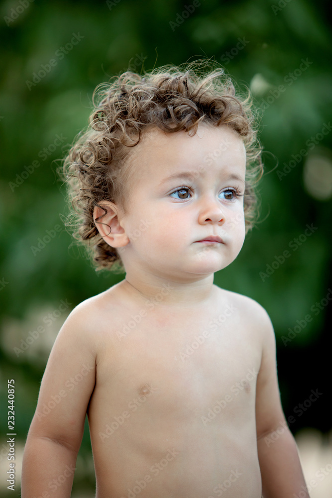 Beautiful baby with curly hair in the garden Beautiful baby with curly hair in the garden