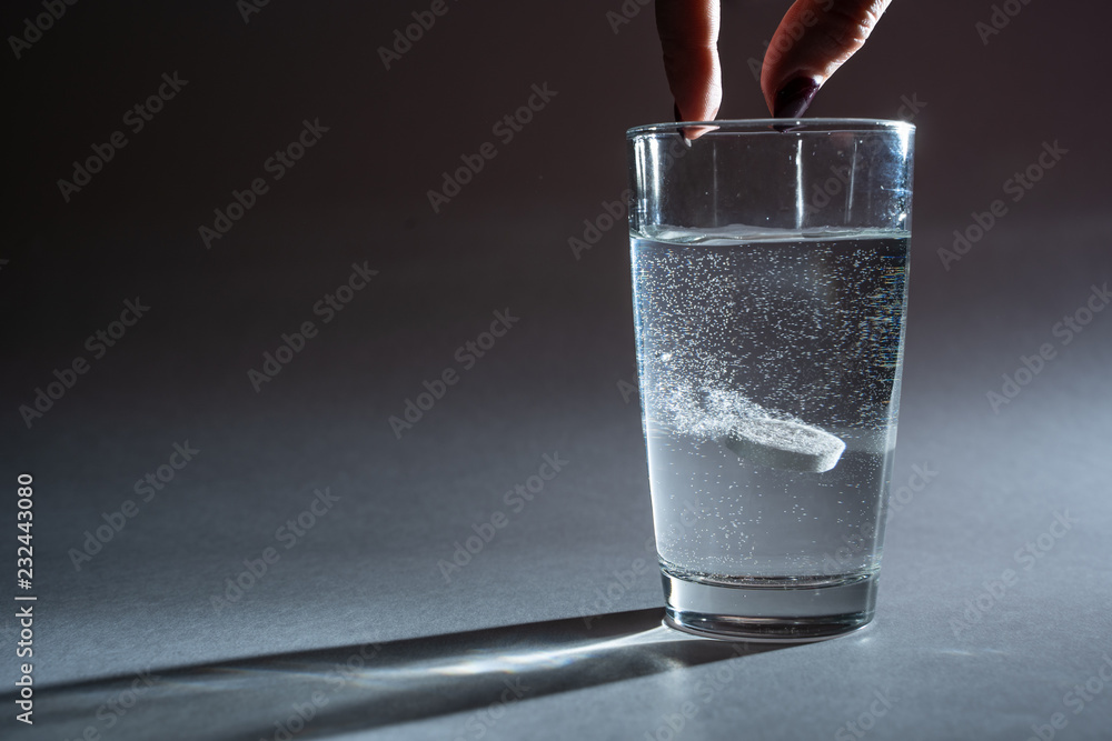 Person throwing vitamin mineral supplement effervescent tablet into