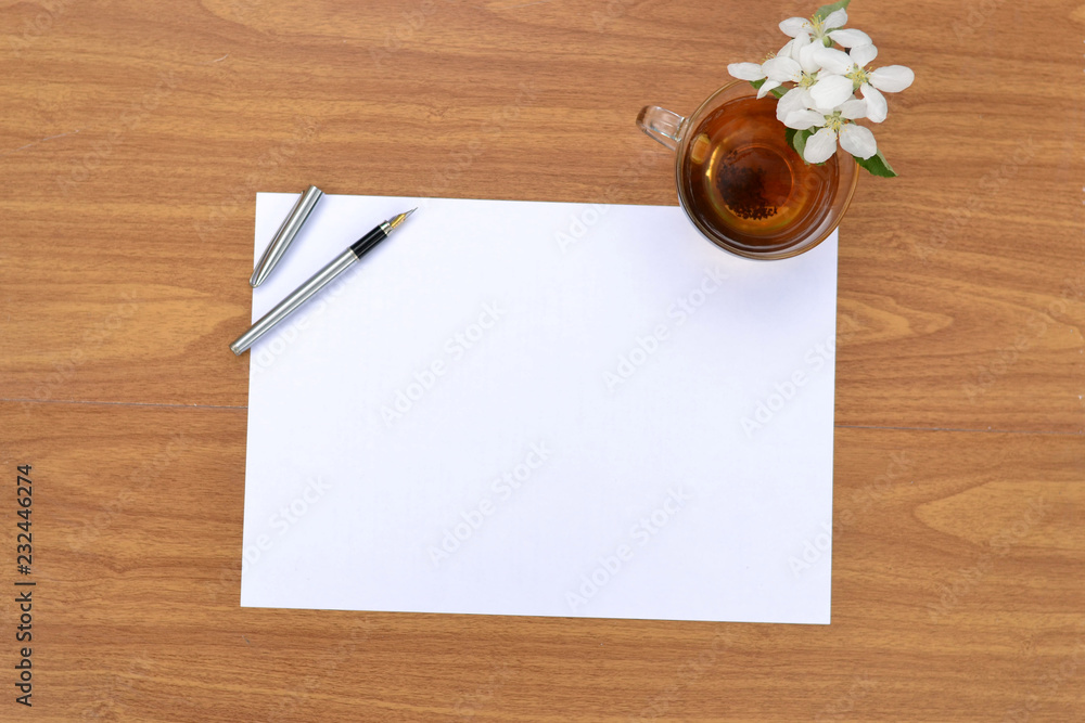 A clean sheet of paper on a wooden surface and a Cup of tea. A clean sheet of paper on a wooden surface and a Cup of tea.