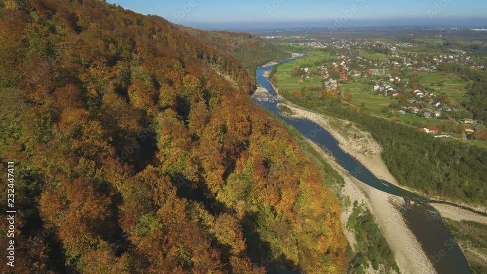 Aerial, top view from Drone: flying over the mountain with forest and river. Forest yellow autumn color. River at the foot of the mountain. Aerial, top view from Drone: flying over the mountain with forest and river. Forest yellow autumn color. River at the foot of the mountain.