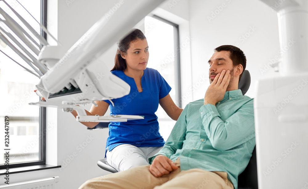 Fototapeta premium medicine, dentistry and healthcare concept - female dentist and male patient suffering from toothache at dental clinic