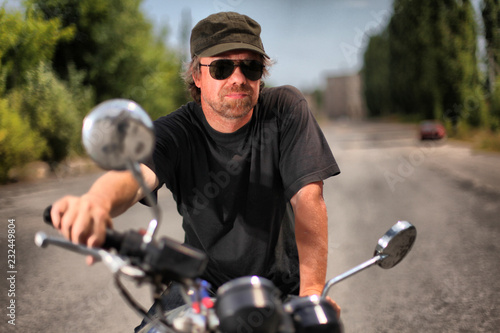 Brutal white man in black glasses on a motorcycle.