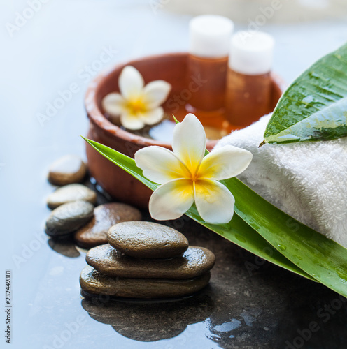 bowl of water with small oil bottles and flower. Spa towel and stone. Body care and spa concept