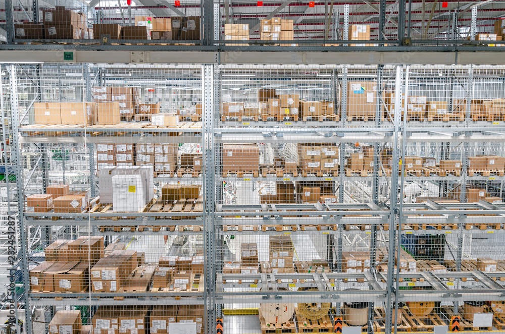 Large cardboard boxes on shelves closed metal mesh in a warehouse in an industrial enterprise. Warehouse technologies, employment at the factory. Arrangement of goods. Parcel delivery. Large cardboard boxes on shelves closed metal mesh in a warehouse in an industrial enterprise. Warehouse technologies, employment at the factory. Arrangement of goods. Parcel delivery.