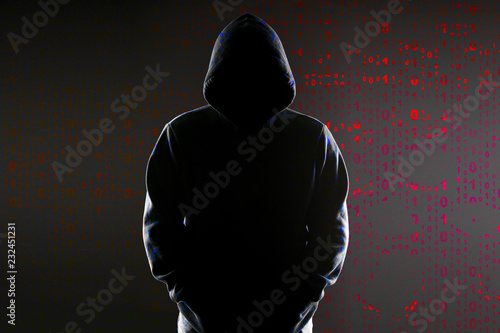 Silhouette of a hacker on black with binary codes on background