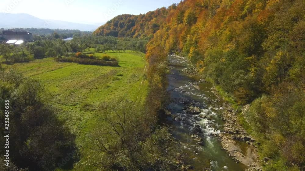 Aerial, top view from Drone: flying over the mountain with forest and river. Forest yellow autumn color. River at the foot of the mountain. Aerial, top view from Drone: flying over the mountain with forest and river. Forest yellow autumn color. River at the foot of the mountain.