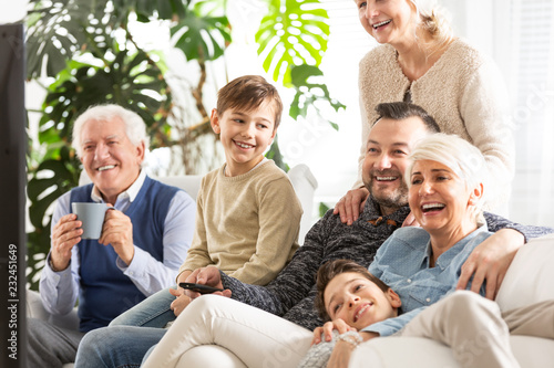 Happy family watching television. Kids sitting next to parents and smiling grandfather