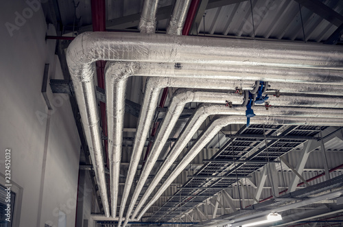 Photos Metal pipes in thermal insulation winding on the ceiling of an industrial enterprise