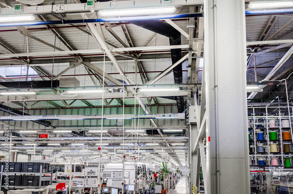interior of a large industrial workshop, luminescent lamps under the ceiling are suspended in rows. Working atmosphere. interior of a large industrial workshop, luminescent lamps under the ceiling are suspended in rows. Working atmosphere.