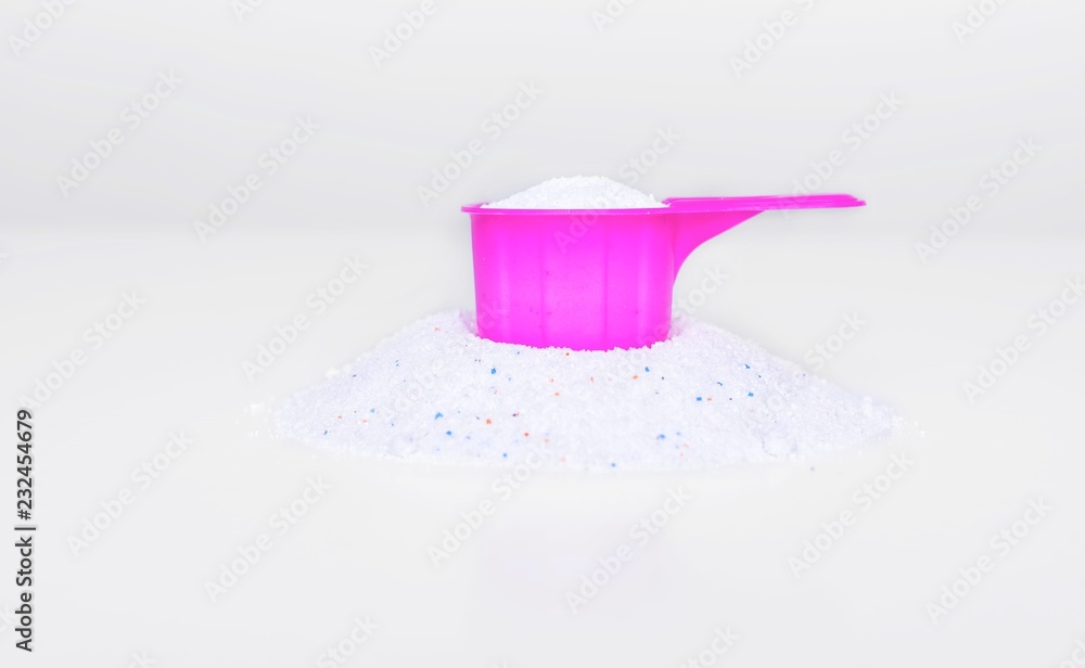 Washing powder in a measuring cup on a white table. Washing powder in a measuring cup on a white table.