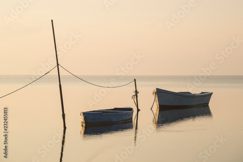 An old traditional fishing boat, moored to a pole in the middle of a coastal lagoon. Picture with a retro style looking.
