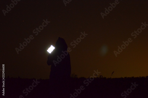 Man in the hood with phone, night, silhouette,