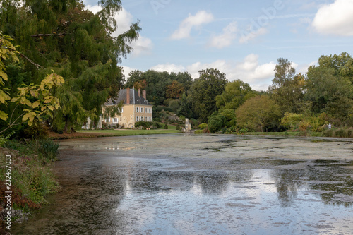 Landscape of French garden in Loire Valley. A lake in the foreground with the reflection of clouds and in a background a small typical castle.