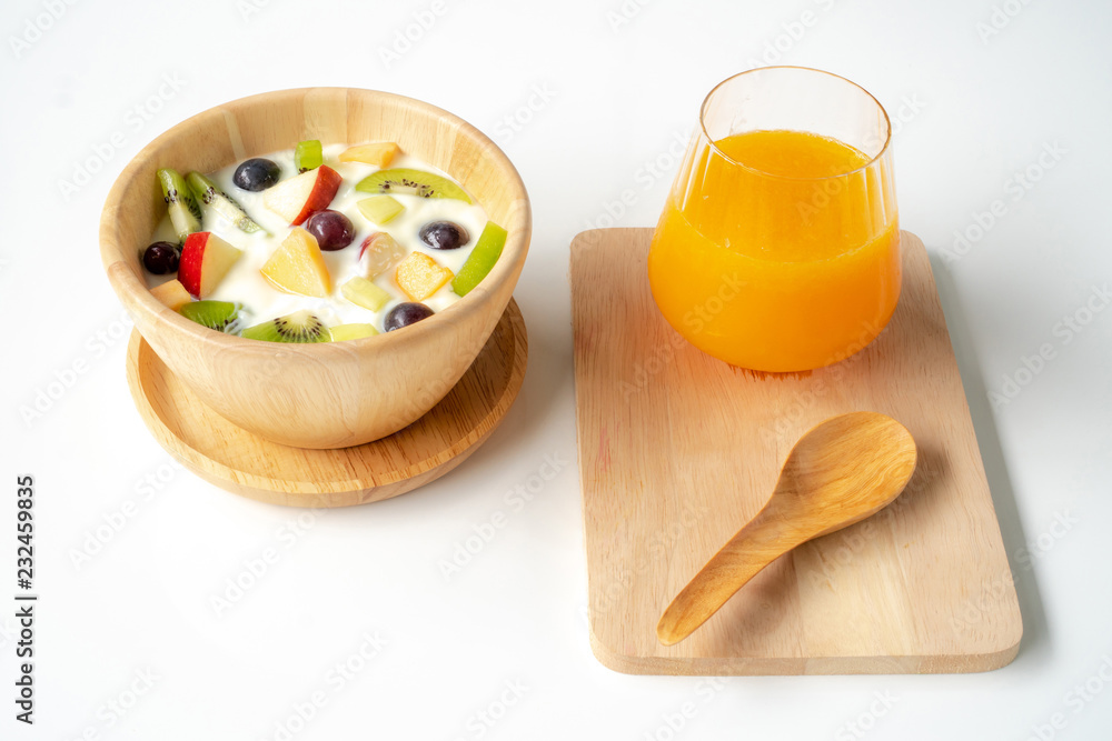 Fruit salad with yogurt on a wooden bowl and orange juice