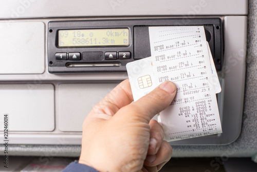 Digital tachograph and drivers hand holding print with driving times of the day