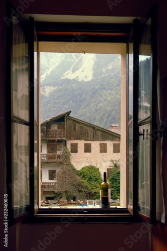 a bottle of wine and 2 glasses on the windowsill of the open window.