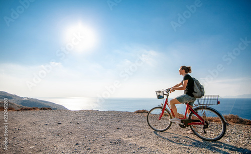 Fototapeta Naklejka Na Ścianę i Meble -  Young beautiful girl woman travels by bicycle on a mountain landscape on the beach in the sun, tourism and leisure concept, Greece, Kos