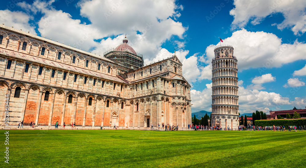 Picturesque spring view of famous Leaning Tower in Pisa. Sunny morning scene with hundreds of tourists in Piazza dei Miracoli (Square of Miracles), Italy, Europe. Traveling concept background.