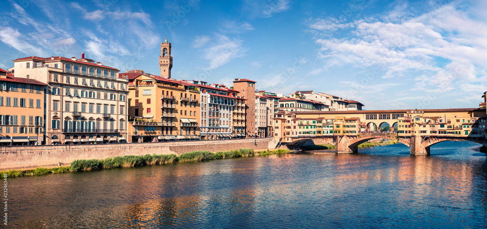 Sunny spring cityscape of Florence with Old Palace (Palazzo Vecchio or Palazzo della Signoria) on background and Ponte Vecchio bridge over Arno river. Colorful morning scene in Italy, Europe.