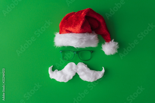 Christmas background. Santa's hat with green glasses and white hipster moustaches and copy space. Flat lay New year minimal.