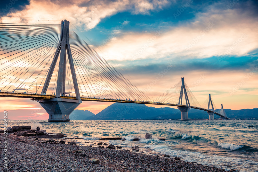 Obraz premium Dramatic evening scene with Rion-Antirion Bridge. Colorful spring scene of the Gulf of Corinth, Greece, Europe. Beauty of countryside concept background. Artistic style post processed photo.