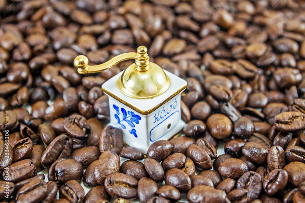 Gold coffee grinder on the coffee beans background