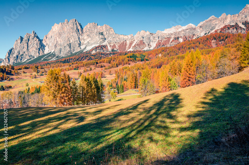 Great sunny view of Dolomite Alps with larch forest. Colorful autumn scene of mountains. Cortina d'Ampezzo location, Italy, Europe. Beauty of nature concept background. 
