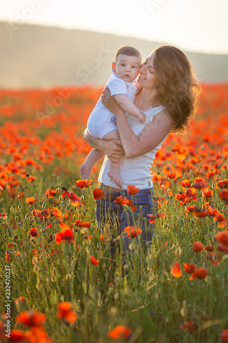 Outdoor portrait. Young mother and her daughter enjoy life time together on a poppy field . Concept of love and happy family. Poppy meadow