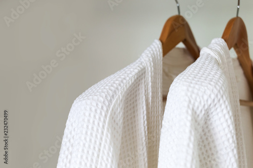 white bathrobe hanging on rack photo