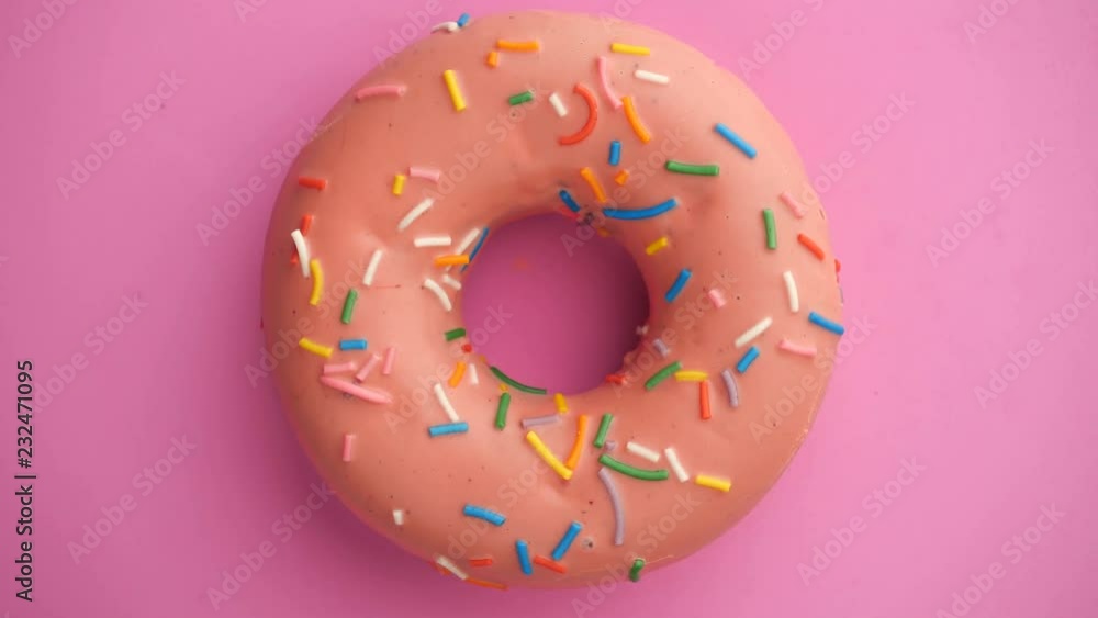 Bright and colorful sprinkled donut close-up shot spinning on a color background.
Top view. Seamless looping.
Bright and colorful sprinkled donut close-up shot spinning on a color background.
Top view. Seamless looping.