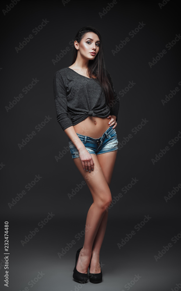 Studio fashion shot: portrait of beautiful young woman in denim shorts and blouse. Model test Studio fashion shot: portrait of beautiful young woman in denim shorts and blouse. Model test