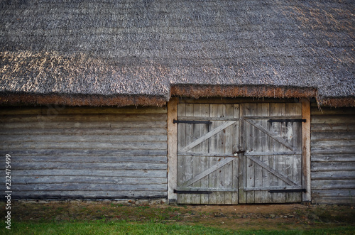Fototapeta Old wooden barn. Log wall, gate and thatched roof.
