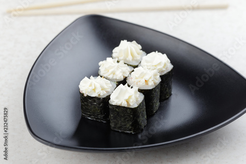 Sushi Maki on a black plate. Triangular black plate with sushi on a light background.