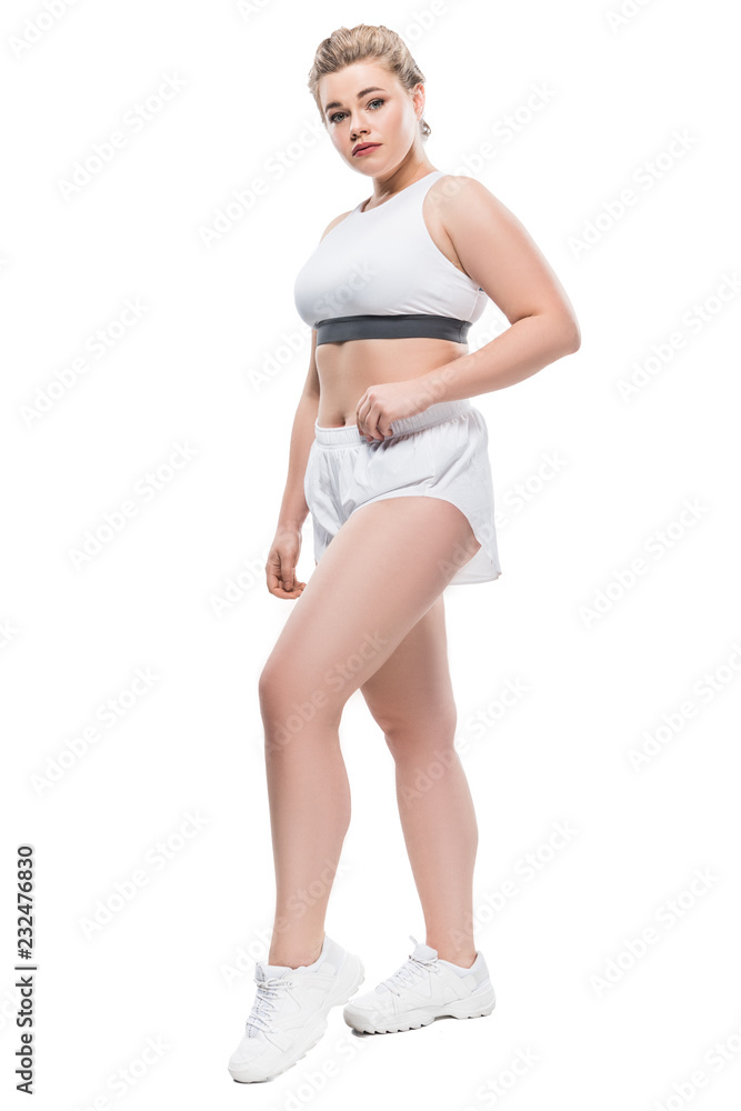 full length view of attractive oversize girl in sportswear looking at camera isolated on white full length view of attractive oversize girl in sportswear looking at camera isolated on white