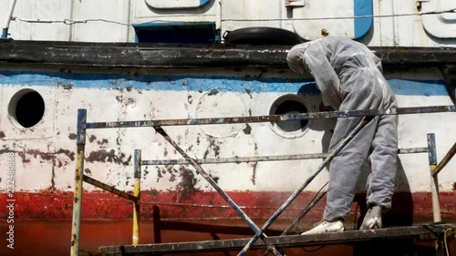 Workers tear off paint on metal in repairs process at shipyard. photo