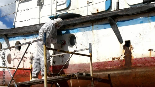 Workers tear off paint on metal in repairs process at shipyard. photo