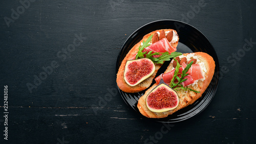 Sandwich with figs, prosciutto and cheese. On the old background. Healthy food. Free space for text. Top view.